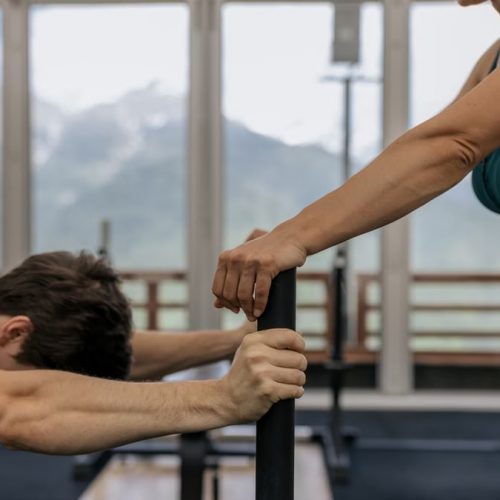 A couple working out together at an indoor gym with mountain views.