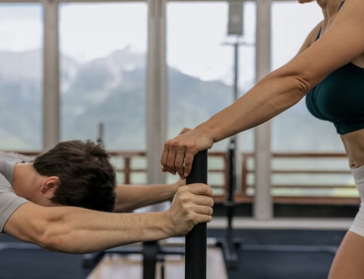 A couple working out together at an indoor gym with mountain views.